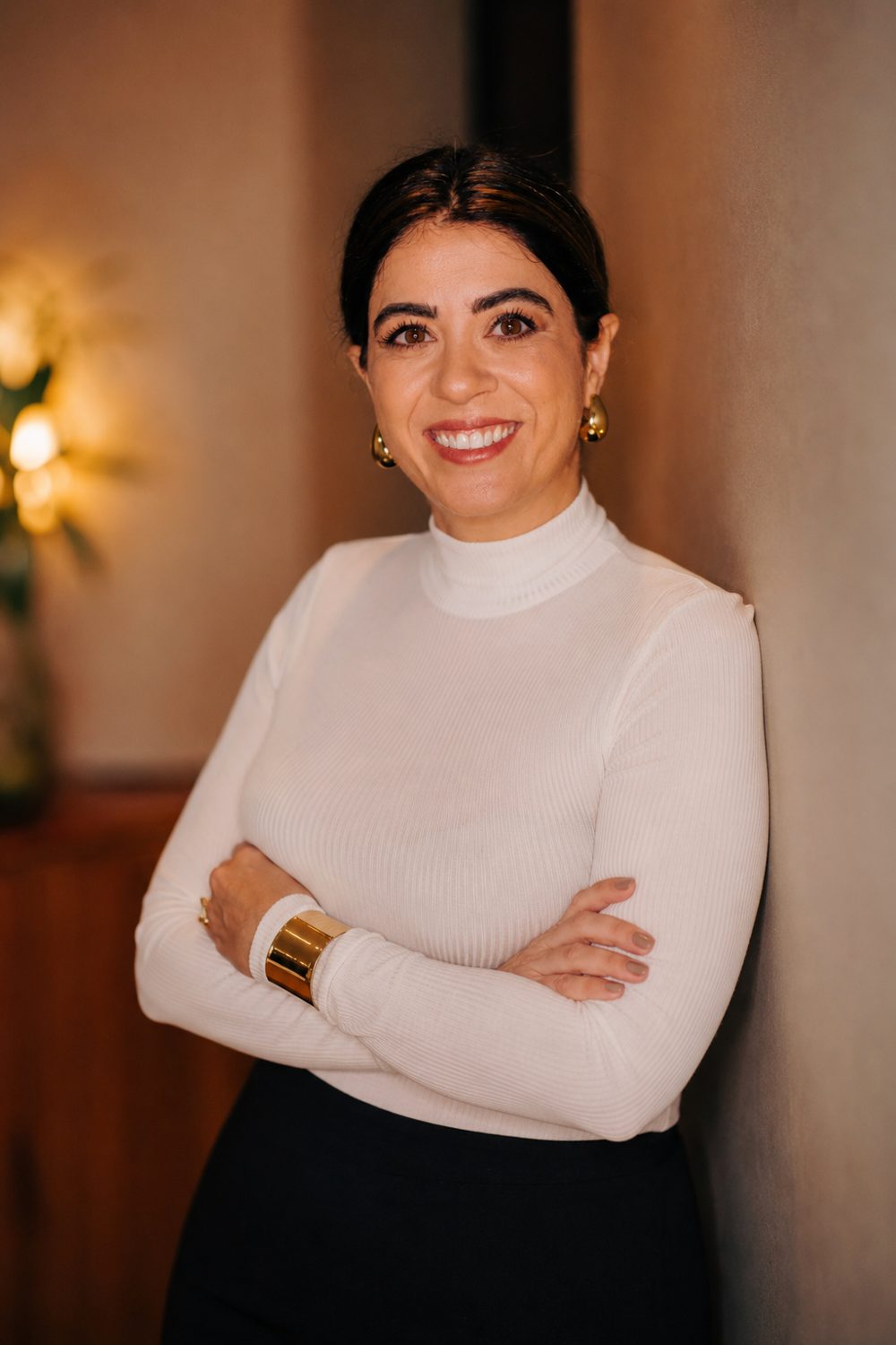 Erika Fernandes de braços cruzados, com blusa branca de gola alta